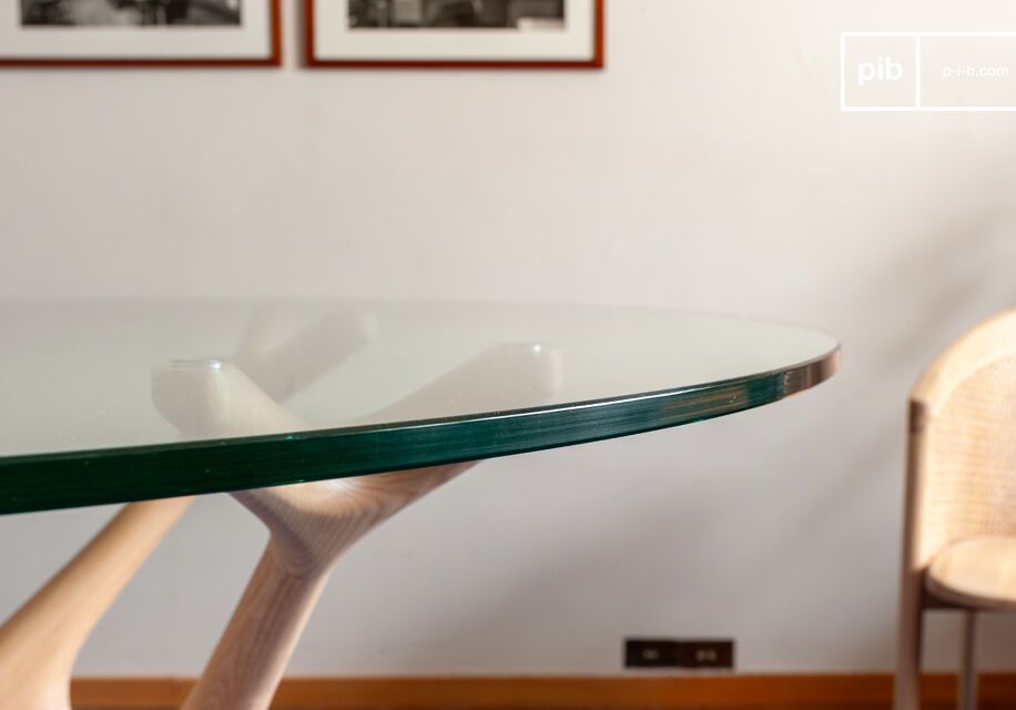 Combina la trasparenza di un piano in vetro temperato con una base scultorea che richiama rami